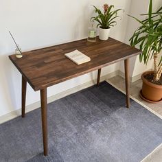 a wooden table with a book on it next to a potted plant and rug