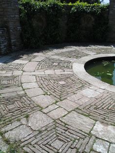 an outdoor fountain surrounded by bricks and grass