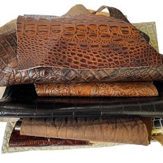 an alligator skin purse is stacked on top of other leathers