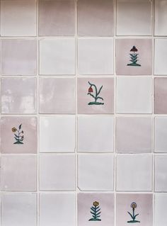 a tiled wall with flowers and plants painted on the tiles in pink, white and green