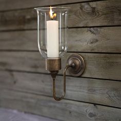 a candle is lit on the wall next to a wood paneled wall with a metal hook