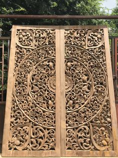 an intricately carved wooden door in front of trees