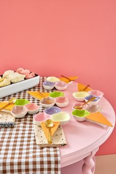 a pink table topped with plates and bowls filled with desserts on top of it