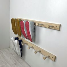 three pairs of shoes are hanging on the wall next to a pair of wooden shoe rack