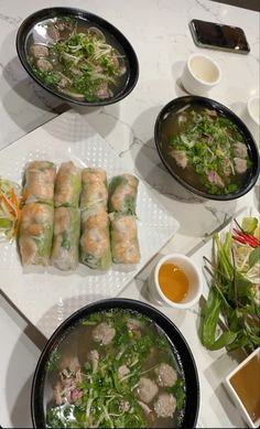 several plates of food on a table with chopsticks and bowls of soup next to them