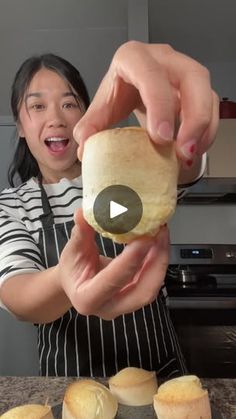 a woman in an apron is holding a roll and making some sort of bread on a cutting board