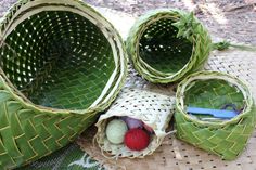 three baskets with yarn and balls of yarn in them on the ground next to some leaves