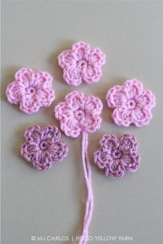 four crocheted flowers are arranged in the shape of a flower on a white surface