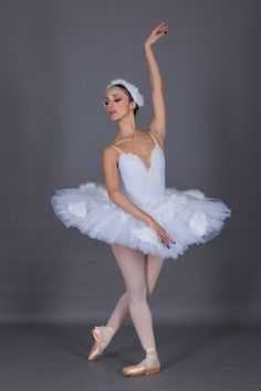 a young ballerina is posing for the camera