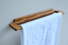 a wooden towel rack hanging on the wall next to a white bathrobe curtain