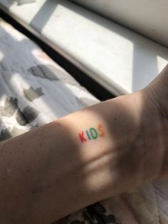 a person's arm with the word kid written on it, in front of a window