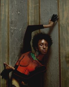 a woman leaning up against a wall with her hand on the back of her head