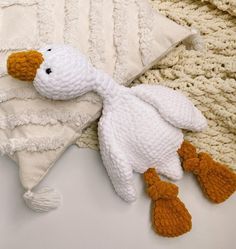 a white stuffed duck laying on top of a pillow