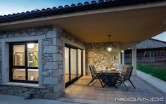 an outdoor dining area with table and chairs next to a stone building at night time