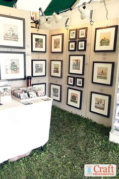 an outdoor booth with pictures on the wall and grass in front of it that has been set up for sale