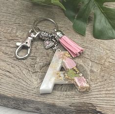 a pink tasseled keychain sitting on top of a piece of wood