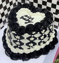 a black and white heart shaped cake sitting on top of a checkered table cloth