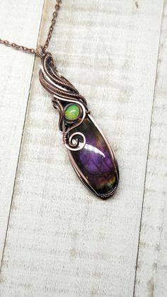 This pendant features a stunning purple Labradorite with mesmerizing color of purple, fuchsia and gold. The stone wrapped in antiqued copper wire in a freeform design, showcasing its natural beauty. A  sparkling natural Opal adds a touch of brilliance to this unique piece. The pendant measures a little over 2 1/2 inches in length and comes with an 18 inch chain and polishing cloth. Spiritual Purple Cabochon Jewelry, Handmade Iridescent Jewelry For Collectors, Handmade Iridescent Collectible Jewelry, Spiritual Purple Jewelry With Large Pendant, Unique Purple Copper Necklace, Purple Gemstone Copper Jewelry, Unique Iridescent Gemstone Necklaces, Purple Cabochon Pendant Jewelry, Unique Iridescent Gemstone Necklace