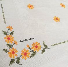 an embroidered tablecloth with yellow flowers on it