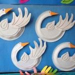 three paper swans are on display in front of a blue background with flowers and leaves