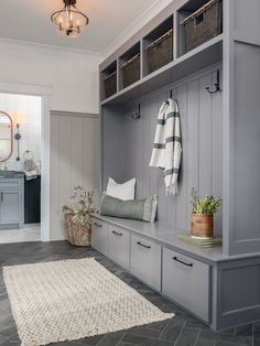 a gray and white entryway with storage cabinets, rugs and baskets on the floor