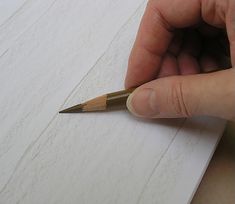 a person holding a pencil in their left hand while writing on a piece of paper