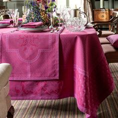 the table is set with pink linens and place settings for two people to sit at