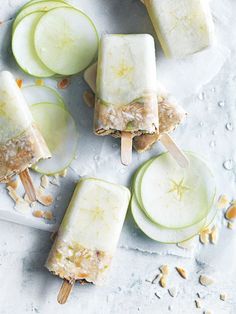 four popsicles with apple slices and peanut butter on them, sitting on a white surface