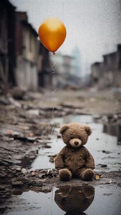 a teddy bear sitting on the ground with a balloon attached to it