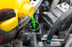 the green liquid is being poured into the car's engine compartment, which has been filled with fuel