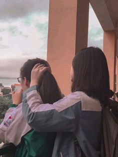 two people standing on a balcony looking out at the ocean