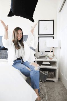 a woman sitting on top of a bed with her arms in the air