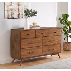 a large wooden dresser sitting next to a plant on top of a hard wood floor