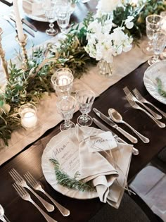 the table is set with silverware and white flowers