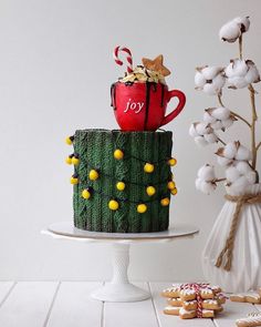 a christmas cake decorated with candy canes and coffee mug sitting on top of it