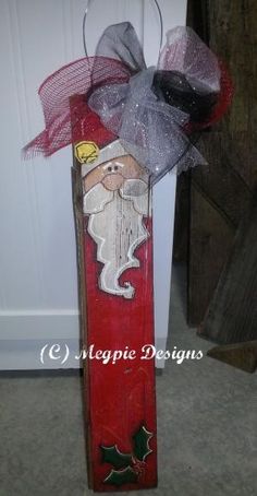 a wooden sign with a santa clause painted on it's side and a bow hanging from the front