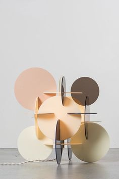 an abstract sculpture made out of different colored circles on top of a white floor next to a wall