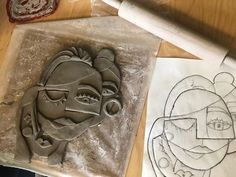 two clay sculptures sitting on top of a table next to some paper and glues