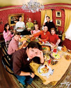 a group of people sitting around a dining room table with food in front of them