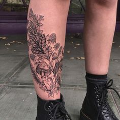 a woman's legs with flowers and leaves tattooed on her leg, while wearing black combat boots