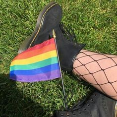 a person wearing black boots and holding a rainbow flag