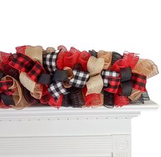 red, black and tan burluck bow on mantle with fireplace mantel in background