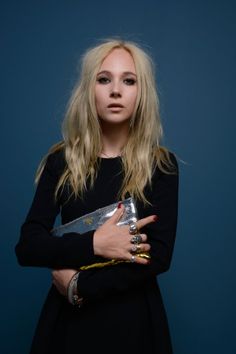 a woman with long blonde hair holding a silver purse