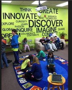 children are sitting on the floor in front of a wall with words written on it