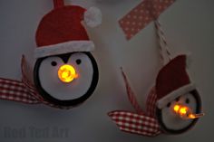 two penguin ornaments with lights in the shape of santa's hats hanging on a wall