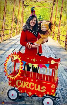 a woman is holding a doll in a red wagon on a bridge that says circus