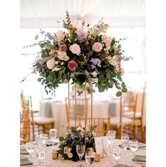 a tall centerpiece with flowers and greenery sits on top of a round table