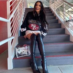 a woman is sitting on the stairs with her legs crossed and wearing high heel boots