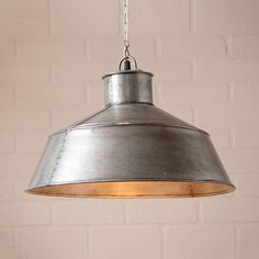 a metal light hanging from a brick wall in a room with white bricks on the walls