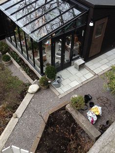 an aerial view of a glass house in the middle of some plants and rocks on the ground